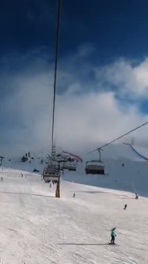 Kablolu sandalyede kayak kaldırmanın birinci şahıs bakış açısı FPV 'nin hızlı ileri etkisi alp kayağı için yükselir. Dolomitler 'de kayak yapan insanlarla kayak pisti. Kayak alanı Belvedere. Canazei, İtalya