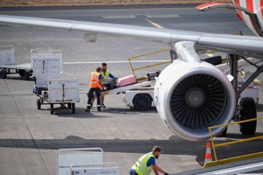 Funchal, Portekiz - 6 Haziran 2024: Havaalanı personeli bavullarını tramvaydan uçağa yüklerken kemer yükleyici bant kullanıyor.