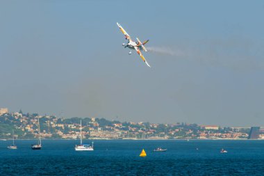 Oeiras, Portekiz - 30 Eylül 2023: Dublör akrobatik uçak Edge 540 mavi gökyüzünde Oeiras Hava Gösterisinde, yat teknelerinin üzerinde gösteri yapıyor.