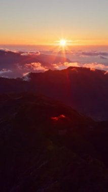 Pico Ruivo 'da gün batımında bulutlu dağların uçuş görüntüsü. Madeira Adası, Portekiz. Dolly hareketine yaklaş.