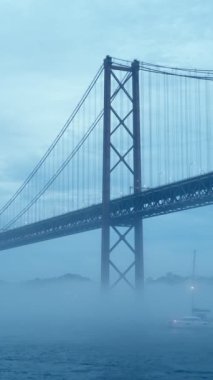 25 de Abril Köprüsü 'nün Lizbon' un ünlü turistik beldesi, Lisboa ve Almada 'yı alacakaranlıkta batan yat tekneleriyle yoğun siste birbirine bağlıyor. Lizbon, Portekiz