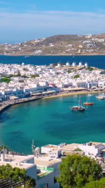 Meşhur yel değirmenleriyle Mykonos şehrinin zaman çizelgesi, tekneleri ve yolcu gemisiyle liman. Mykonos, Cyclades adaları, Yunanistan. Kamera kaydıyla