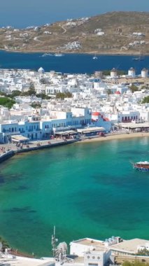 Meşhur yel değirmenleriyle Mykonos kasabası manzarası ve yaz günü tekneleri ve yolcu gemisi olan liman manzarası. Mykonos, Cyclades adaları, Yunanistan. Kamera tavasıyla
