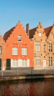 Belçika 'nın ünlü turist kasabası Bruges Brugge' de gün batımında eski evler ve kanallar. Sokaktan geçen bir araba. Yatay kamera tavası