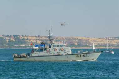 Oeiras, Portugal - Septermber 30, 2023: Westland Lynx military helicopter of Portuguese Navy and Patrol vessel NRP Cassiopeia of the Portuguese Navy at Oeiras Air Show clipart