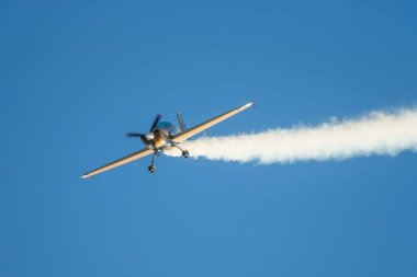 Altın dublör akrobatik uçak mavi gökyüzünde dumanla gösteri yapıyor. Hız kavramı, zorluk, kesinlik, risk