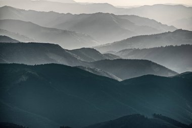 Karpat Dağları yaz günbatımı manzarası soyut dağ tepelerinin mavi renkleriyle gradyanı, doğal seyahat arka planı
