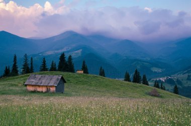 Karpat Dağları yaz manzarası bulutlu gökyüzü ve ev, doğal yaz yolculuğu arka planı.