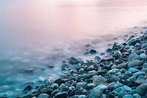 Deniz kıyıları, kayalar ve dalgalarla dolu rüya gibi doğal bir arka plan. Uzun pozlama