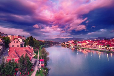 Maribor şehrinin güzel manzarası, Slovenya, güneşin doğuşu, nehir ve dramatik gökyüzü. Açık havada dolaşın..