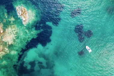 Yunanistan 'da güzel bir Akdeniz. Mavi deniz suyu ve tek bir tekneyle tropikal sakin yaz manzarasının havadan soyut görüntüsü