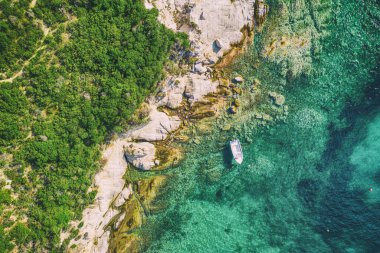 Yunanistan 'da güzel bir Akdeniz. Mavi deniz suyu ve tek bir tekneyle tropikal sakin yaz manzarasının havadan soyut görüntüsü