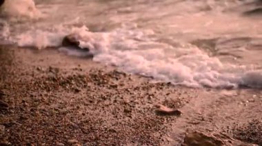 Sahilde deniz sörfü, beyaz köpüklü su çakıl taşlı plaja sıçrıyor, doğal yaz tatili rahatlatıcı konsept.