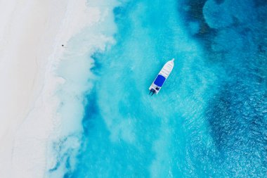 Saona adasındaki güzel Karayip plajı, Dominik Cumhuriyeti. Mavi deniz suyu, beyaz kum ve tek bir tekneyle tropikal sakin yaz manzarasının havadan soyut görüntüsü.