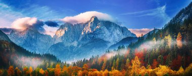 Güneşin doğuşuyla Triglav dağı zirvesi sabah ışığında güzel bulutlarla. Slovenya, Triglav Ulusal Parkı
