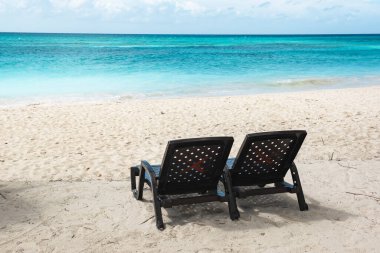 Saona adasındaki güzel Karayip plajı, Dominik Cumhuriyeti. İki sahil şezlonglu, deniz kıyısı ve beyaz kumsallı tropikal cennet manzarası