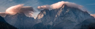 Güneşin doğuşuyla Triglav dağı zirvesi sabah ışığında güzel bulutlarla. Slovenya, Triglav Ulusal Parkı. Panoramik görünüm.