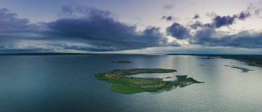Kırsal yaz günbatımı manzarası nehir, küçük ada ve dramatik renkli gökyüzü, doğal arka plan, havadan panoramik manzara