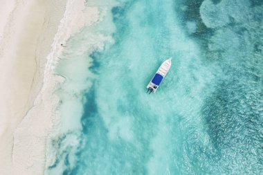 Saona adasındaki güzel Karayip plajı, Dominik Cumhuriyeti. Mavi deniz suyu, beyaz kum ve tek bir tekneyle tropikal sakin yaz manzarasının havadan soyut görüntüsü.