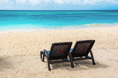 Saona adasındaki güzel Karayip plajı, Dominik Cumhuriyeti. İki sahil şezlonglu, deniz kıyısı ve beyaz kumsallı tropikal cennet manzarası