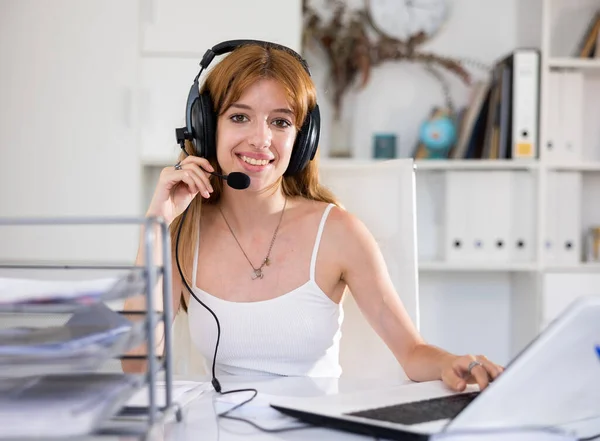 在公司办公室用耳机与客户交谈时 微笑的女操作员 — 图库照片