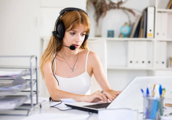 迷人的年轻女性在呼叫中心工作时使用带麦克风和笔记本电脑的耳机 — 图库照片