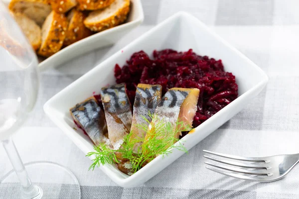 Sliced cold-smoked mackerel fish with boiled beet salad, garnished with fresh dill