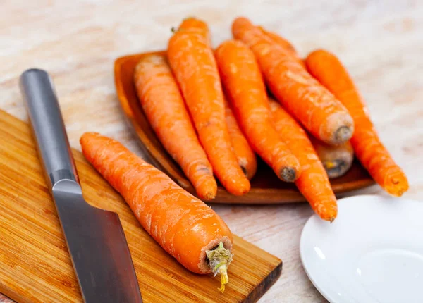 厨房桌子上的木制盘子里的新鲜有机胡萝卜 — 图库照片