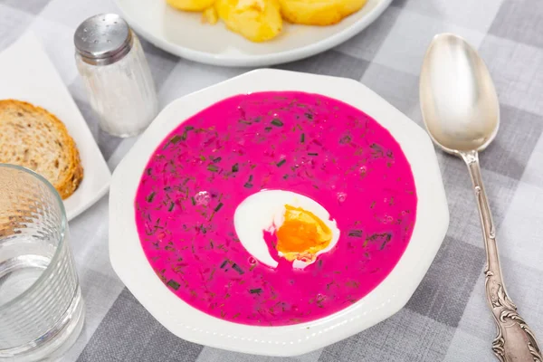 Traditional Belarusian cold vegetable soup Holodnik with beetroot and egg on chekered tablecloth