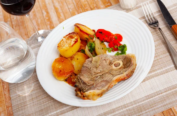 Oven baked lamb leg garnished with potatoes and peppers