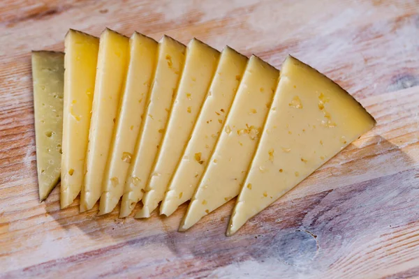 Slices of semi-hard cheese on wooden surface