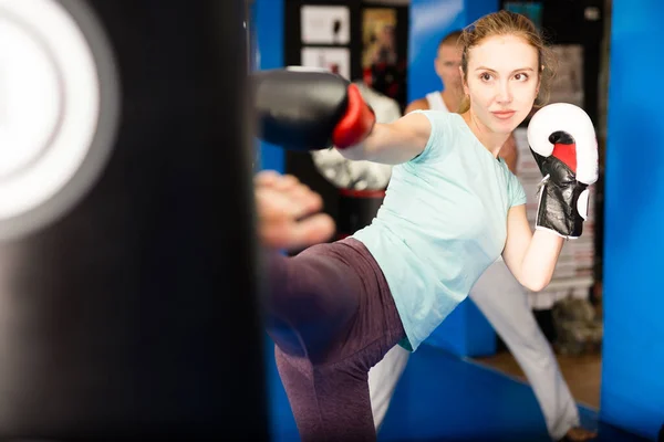 Kvinna Boxningshandskar Sparkar Boxningssäck Träningen Tränaren Står Bakom Och Tittar — Stockfoto