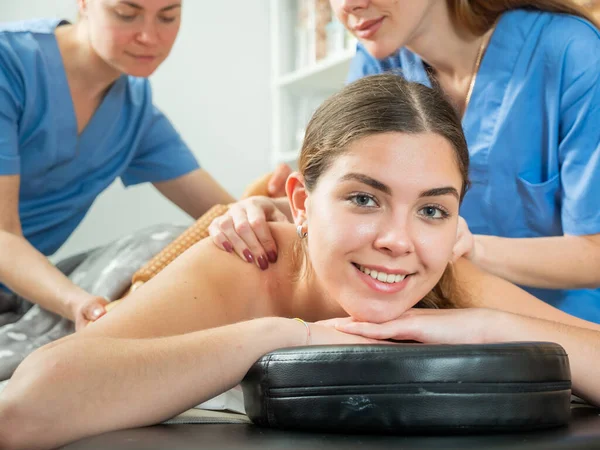 Zufriedene Mädchen Entspannen Wellness Center Während Zwei Professionelle Massagisten Rückenmaderotherapie — Stockfoto