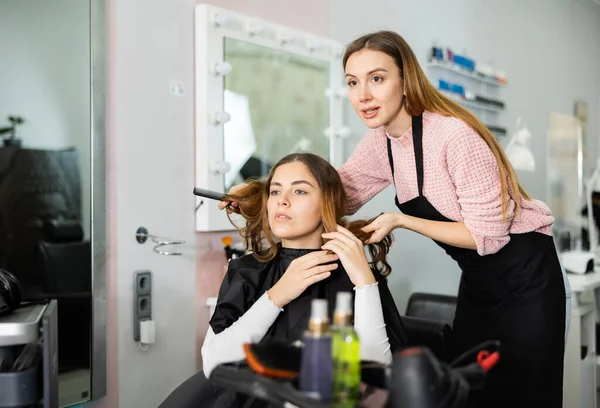 若い女の子のクライアントに現代的なヘアスタイルを提供する熟練した女性の美容師は プロのヘアサロンを訪問 — ストック写真