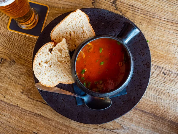 Stock image Portion of just cooked tomato soup served on wooden table in restoraunt.