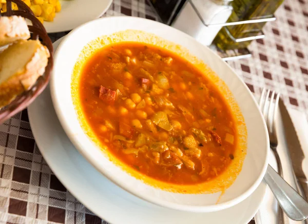 Spanish soup cooked chickpeas, pepper and beef tripe, served at white bowl
