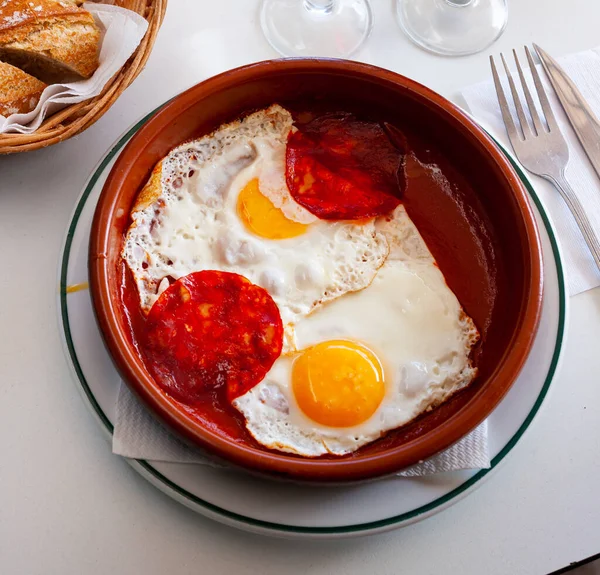 Fried sunny-side-up eggs with sausage and tomatoes in bowl..
