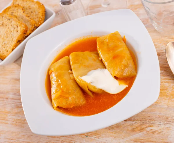 stock image Cabbage rolls with sour cream served on plate. Russian cuisine dish on table.