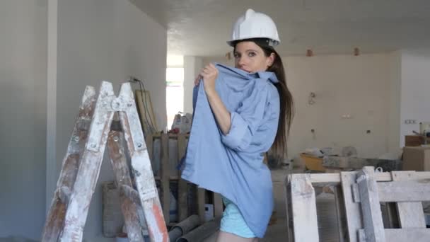 여성은 사다리 근처에 파란색 셔츠와 반바지와 보호용 헬멧을 손으로 가슴을 — 비디오
