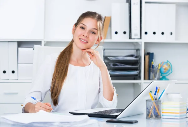 成功的女青年在工作场所使用笔记本电脑 — 图库照片
