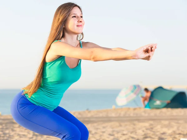 Mavi Cüppeli Gülümseyen Genç Kadın Plajda Isınma Egzersizleri Yapıyor — Stok fotoğraf