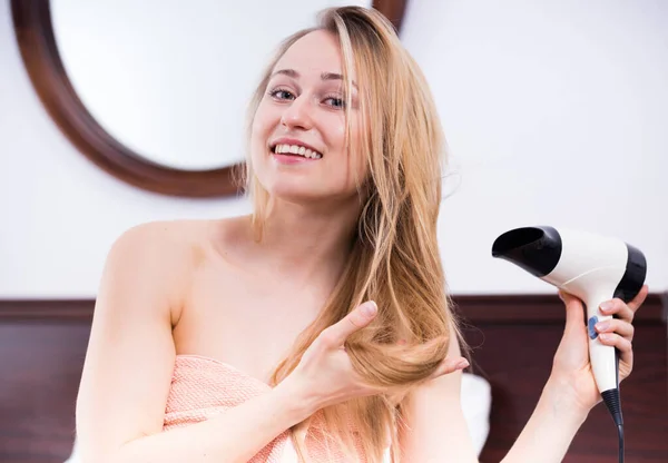明るい若い女性はシャワーの後髪をスタイリングするためにヘアドライヤーを使って — ストック写真