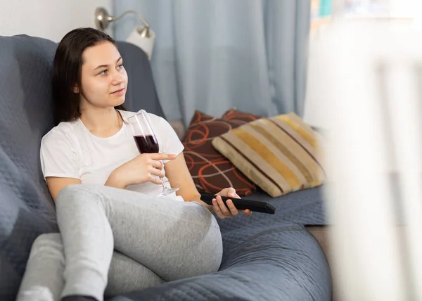 年轻女人在家里的沙发上休息 喝酒看电视 — 图库照片