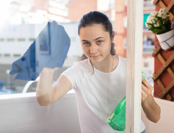 使用海绵和喷雾清洁剂清洗窗户的年轻妇女 — 图库照片