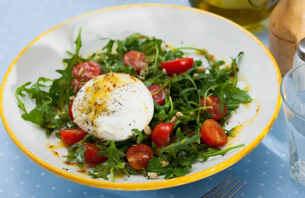 stock image Close up of salad with burrata cheese, pine nuts, cherry tomatoes and arugula with spice at plate