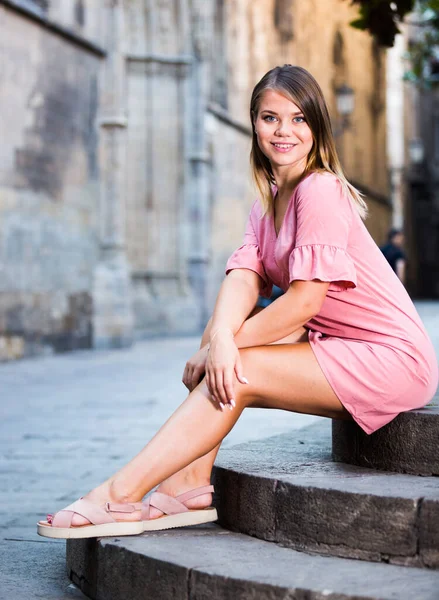 街の風景と背景に石のベンチに座って魅力的な若い女性の肖像画 — ストック写真