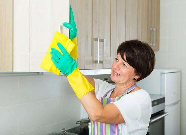 室内用除尘器和洗涤剂擦拭表面的成熟女人 — 图库照片