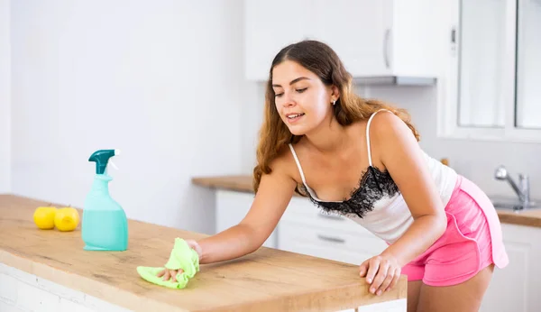 Young woman housewife cleaning furniture at home kitchen