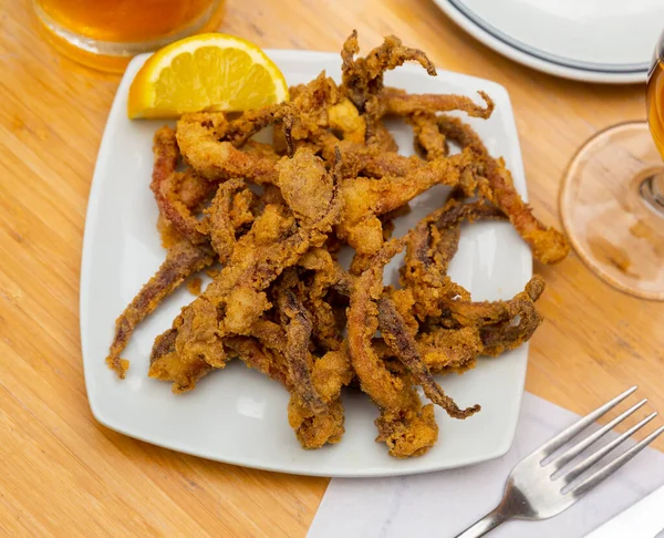 stock image Fried spicy tentacles squid served on white plate with lemon slices