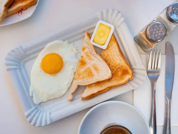 在自助餐厅的饭桌上 用烤土司和配料黄油把煎蛋倒入盘中 — 图库照片